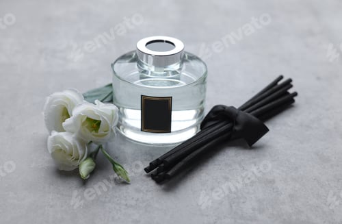 Preview: Reed sticks, glass bottle with aromatic liquid and eustoma flowers on gray marble table
