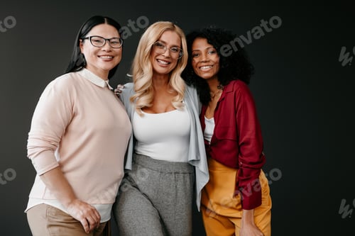 Preview: Three happy mature women bonding and smiling against grey background