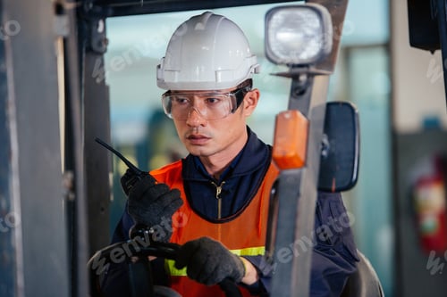 Preview: Asian forklift driver talking on walkie talkie while delivering product