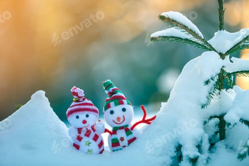 Preview: Two small funny toys baby snowman in knitted hats and scarves in deep snow