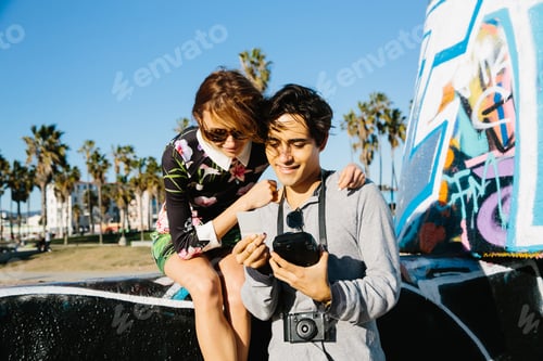 Preview: Young couple outdoors, looking at instant film photograph