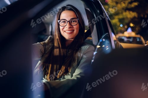 Preview: Business woman driving a car in a city during a night