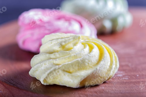 Preview: Colored meringues on wooden board.