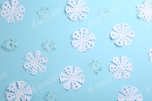 Preview: Many paper snowflakes on light blue background, flat lay