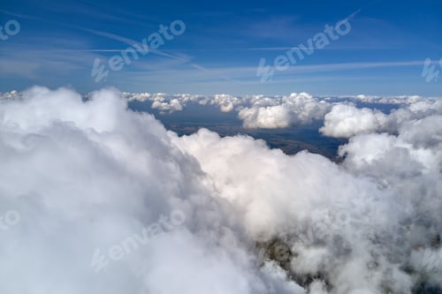 Preview: Aerial view from airplane window at high altitude of earth covered with white puffy cumulus clouds