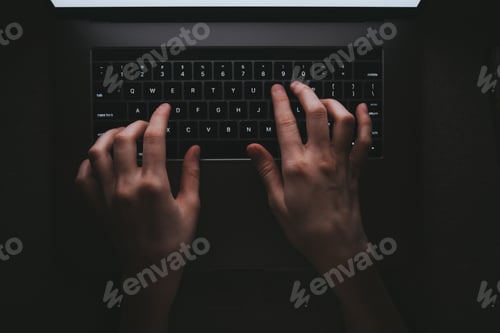 Preview: Woman is typing on a laptop keyboard while lying on a sofa at home in the dark. White laptop screen