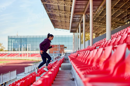 Preview: Woman Exercising by Running Up Stadium Stairs on a Sunny Day Outdoors