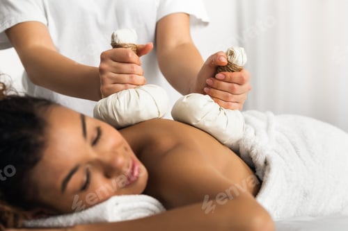 Preview: Therapist applying herbal compresses for black lady
