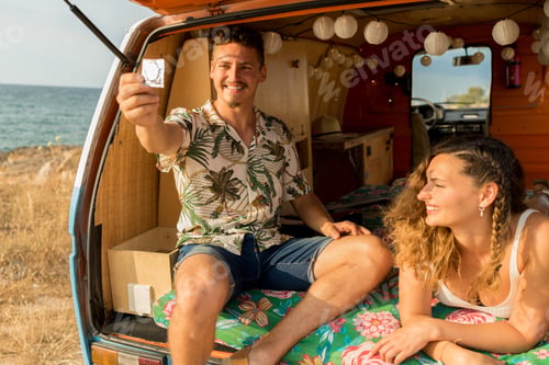 Preview: Man holding a condom next to a woman inside a van