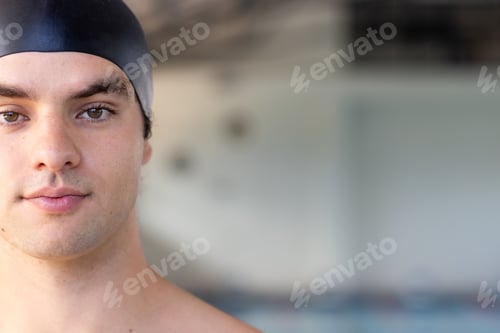 Preview: Caucasian young male swimmer indoors, wearing a black cap, looking at the camera, copy space