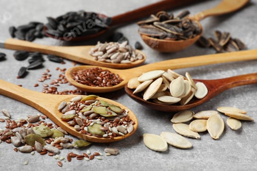 Preview: Different seeds in spoons on grey table, closeup