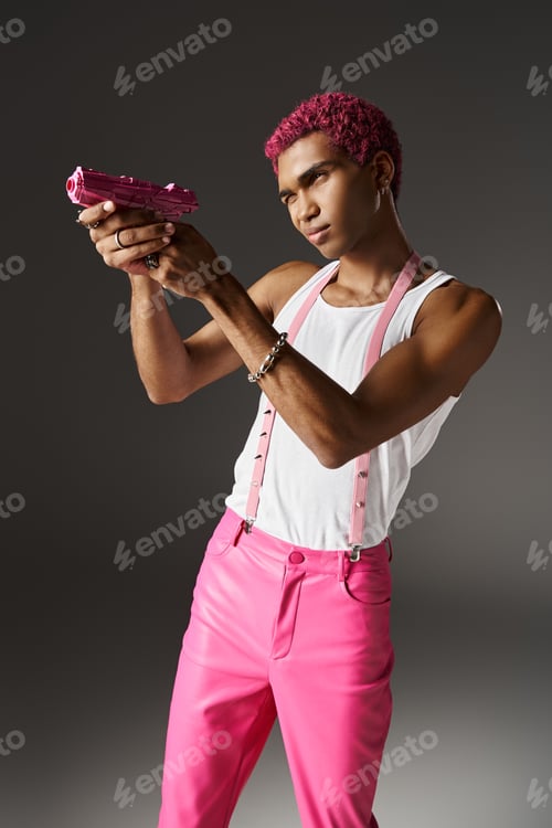 Preview: handsome stylish man in pink pants with suspenders with silver accessories aiming his pink toy gun