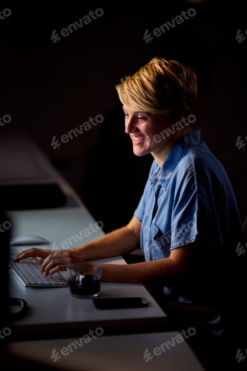 Preview: Businesswoman Working Late In Office With Face Illuminated By Computer Screen