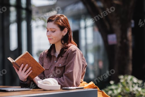 Vista previa: Young woman reading book outdoors enjoying leisure