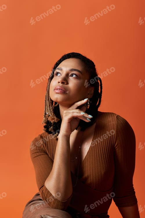 Preview: Young African American woman with braids posing thoughtfully in a vibrant studio