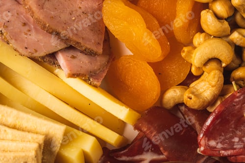 Preview: close up of charcuterie board with different types of nuts, pastrami, salami, apricot and cheese