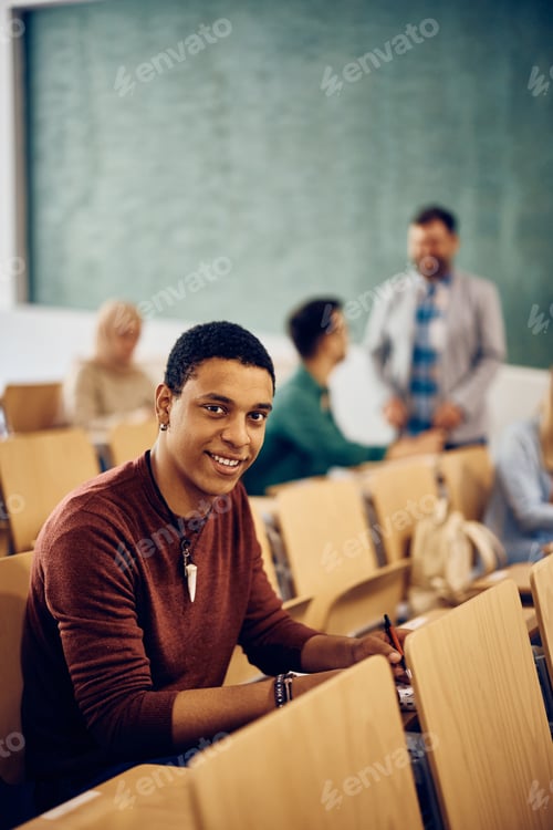 Preview: Happy black student attending a class at the university and looking at camera.