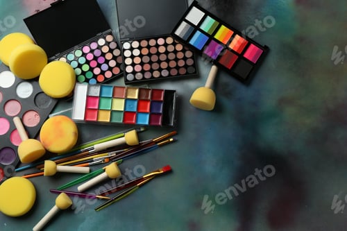 Preview: Bright face paints, brushes and sponges on color background, flat lay. Space for text