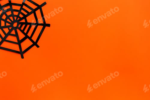 Preview: Halloween festive concept. Decorative spider net on a bright orange background. Flat lay, copy space