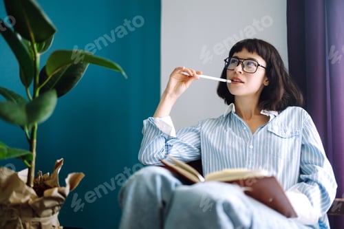 Preview: Young woman at home writing and working with Notebook. Freelancer works and makes notes.