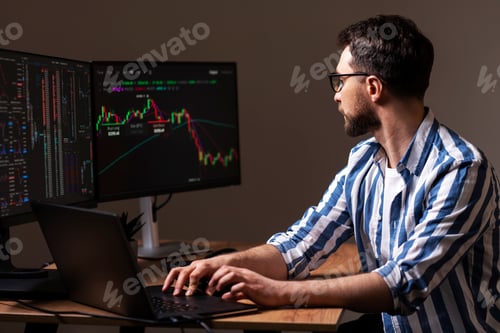 Preview: Trader looking at computer monitor, working online with crypto chart sitting in modern office