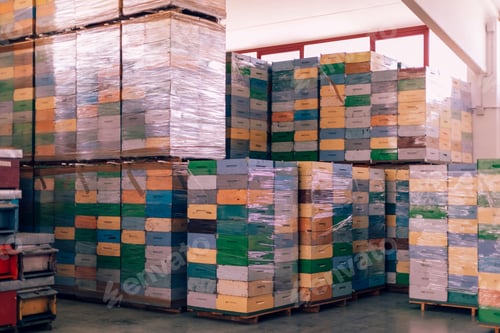 Preview: Colorful beehive boxes stacked and wrapped in plastic in warehouse