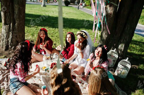 Preview: Seven happy and sexy girls sitting at picnic table and eating strawberries on bachelorette party