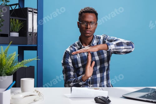 Preview: Organization leader gesturing timeout symbol with hands while in office workspace