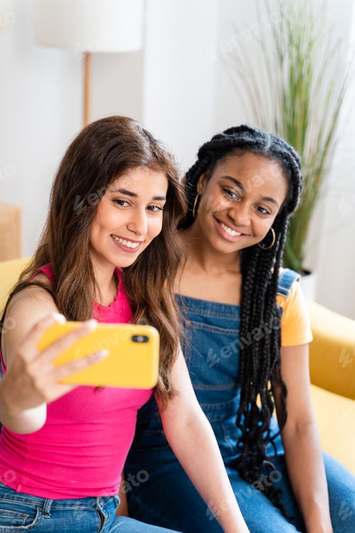 Preview: Happy female friends taking a selfie at home.