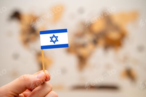 Preview: Israrel flag in mans hand on the world map background.