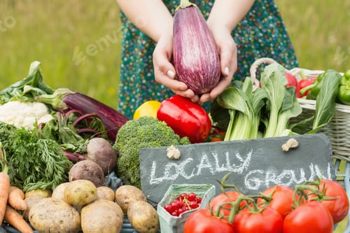 Preview: Female Hands Holding An Aubergine Above Table Of Vegetables