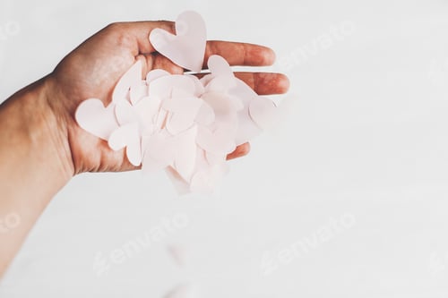 Preview: Hand holding cute pink pastel hearts on white background