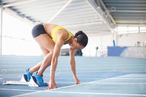Preview: Young female athlete on starting blocks