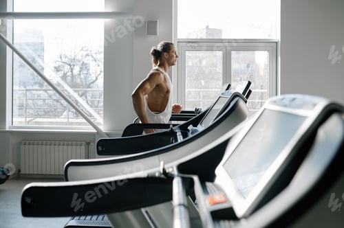 Preview: Strong muscular man running on treadmill at modern sport gym