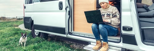Preview: Woman teleworking sitting in the door of a camper van