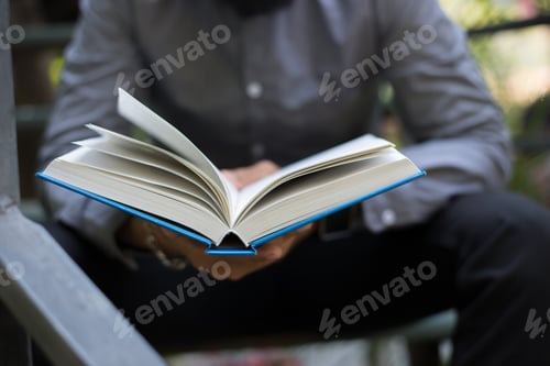 Preview: Young hipster beard man reading books in home garden with nature. Education concept.