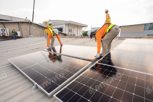 Preview: Team technicians carrying photovoltaic solar moduls on roof of factory.