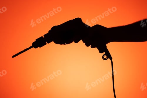 Preview: Hand holding a drill with drill bit in place. Silhouette on orange background