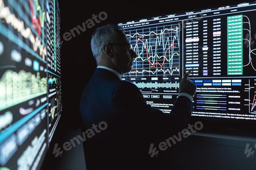 Preview: The businessman stands near the big digital screen in the dark office