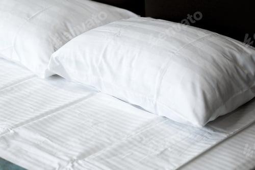 Preview: Soft white pillows placed neatly on a comfortable bed in a cozy room setting