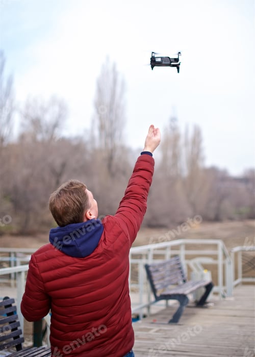 Preview: Rear view of young man launching a drone from the hands
