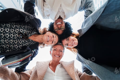 Preview: Bottom view of a group of business women standing on a circle together smiling and looking down to