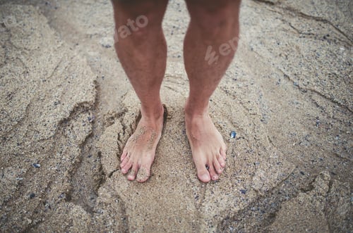 Preview: Man's bare feet in the sand on the beach