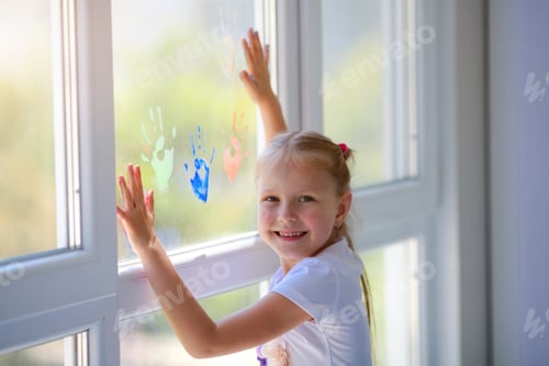 Preview: Children girl draw with palms on the window.