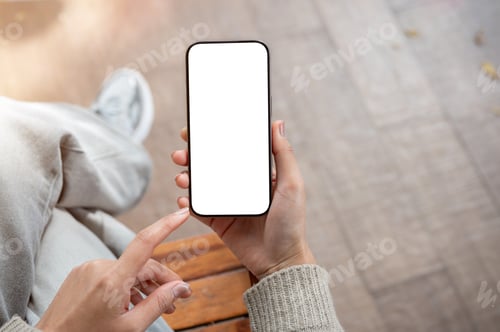 Preview: Top view of a woman uses her phone while sitting indoors. the smartphone with a white screen mockup