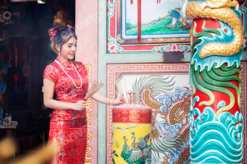 Preview: Chinese woman in red cheongsam dress holding incense pay homage to Chinese god at shrine.
