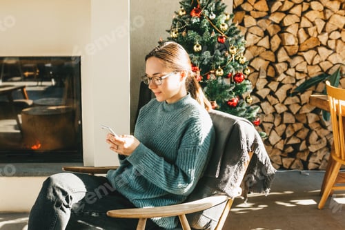 Preview: Woman Relaxing in Chair with Smartphone Near Christmas