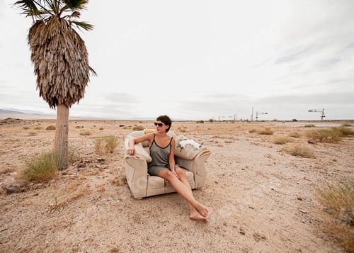 Preview: Young woman relaxing in armchair in desert