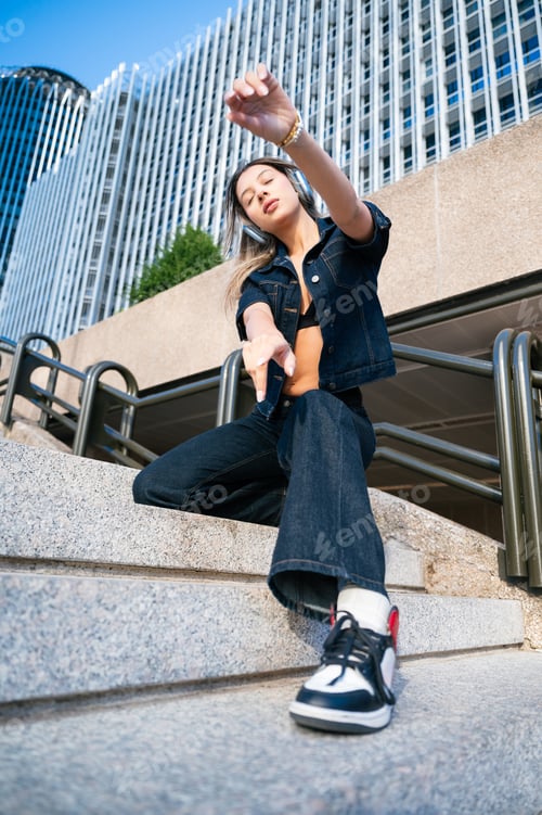 Preview: Stylish woman wearing headphones dancing in urban setting