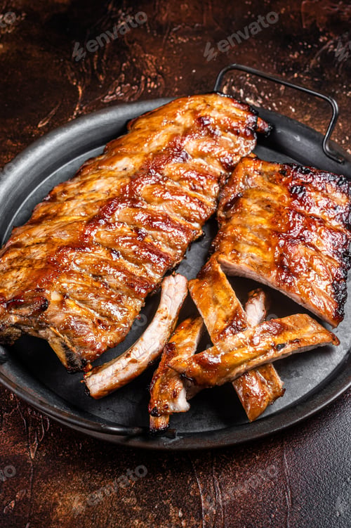 Preview: BBQ pork spare ribs St Louis with hot honey marinade in a steel tray. Dark background. Top view